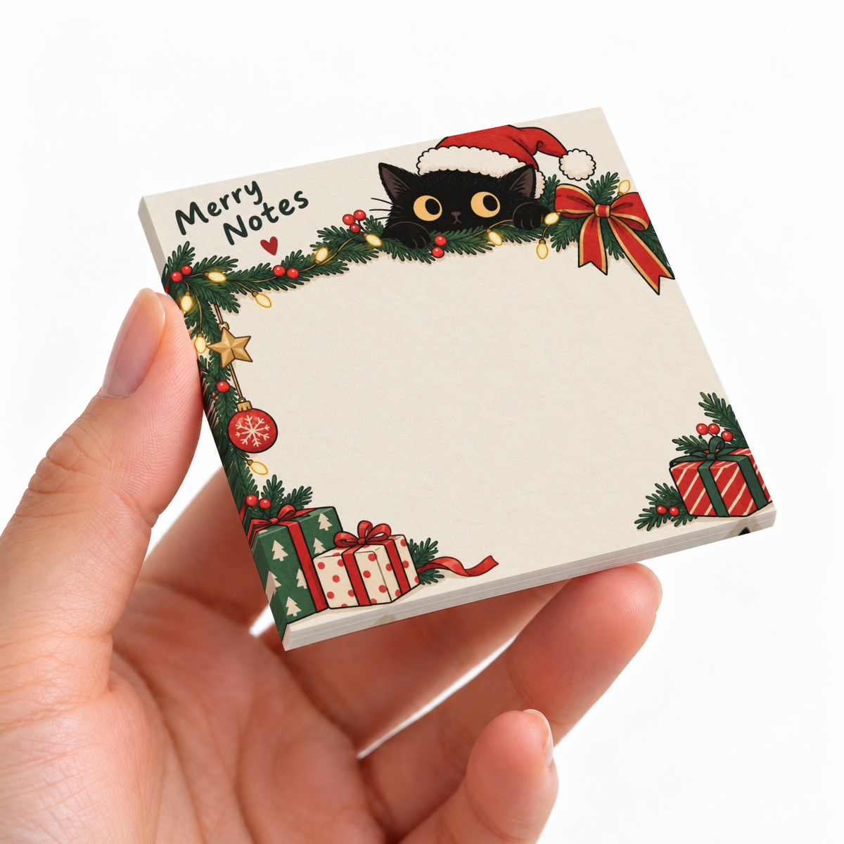 A hand holds a square sticky note pad featuring a black cat in a Santa hat, Christmas greenery, gifts, and Merry Notes.