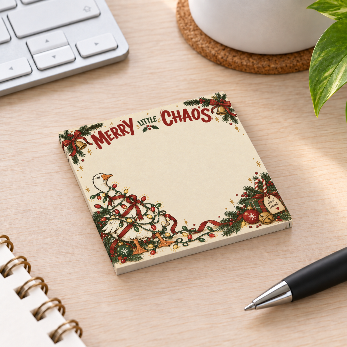 A Christmas goose sticky note pad with tangled lights and “Merry Little Chaos” sits beside a pen and keyboard.