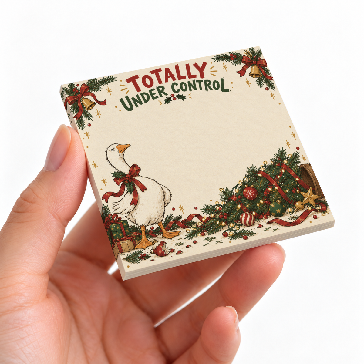 Hand holding a Totally Under Control sticky note pad with a goose beside a fallen decorated Christmas tree.