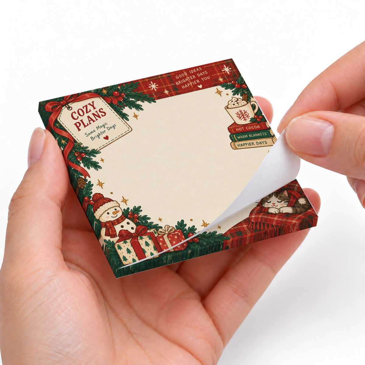 Hands peel a sheet from a Christmas cat and cocoa sticky note pad decorated with holly, gifts, and a snowman.