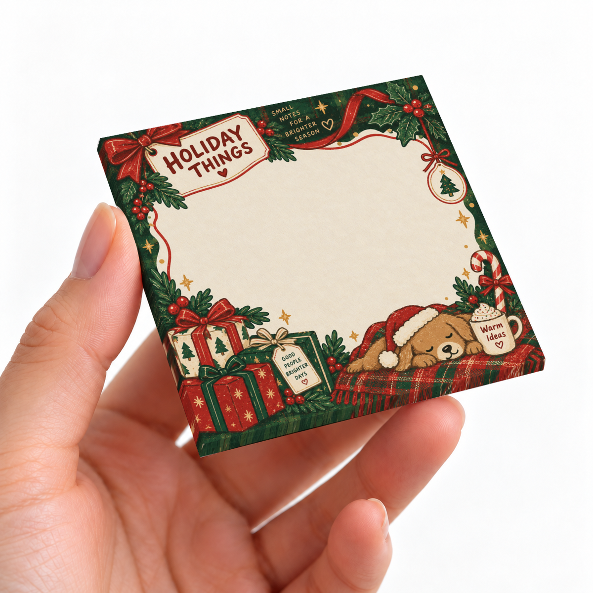 Hand holding a Holiday Puppy and Presents sticky note pad with gifts, greenery, and a sleeping dog.