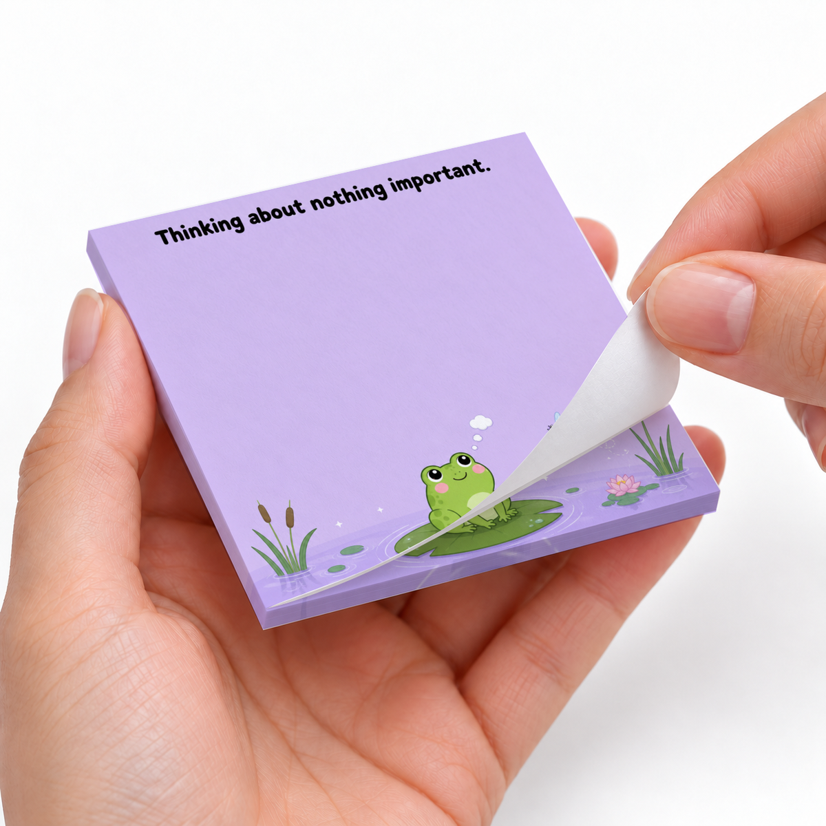 Hands peel a sheet from a purple frog pond sticky note pad reading “Thinking about nothing important.”