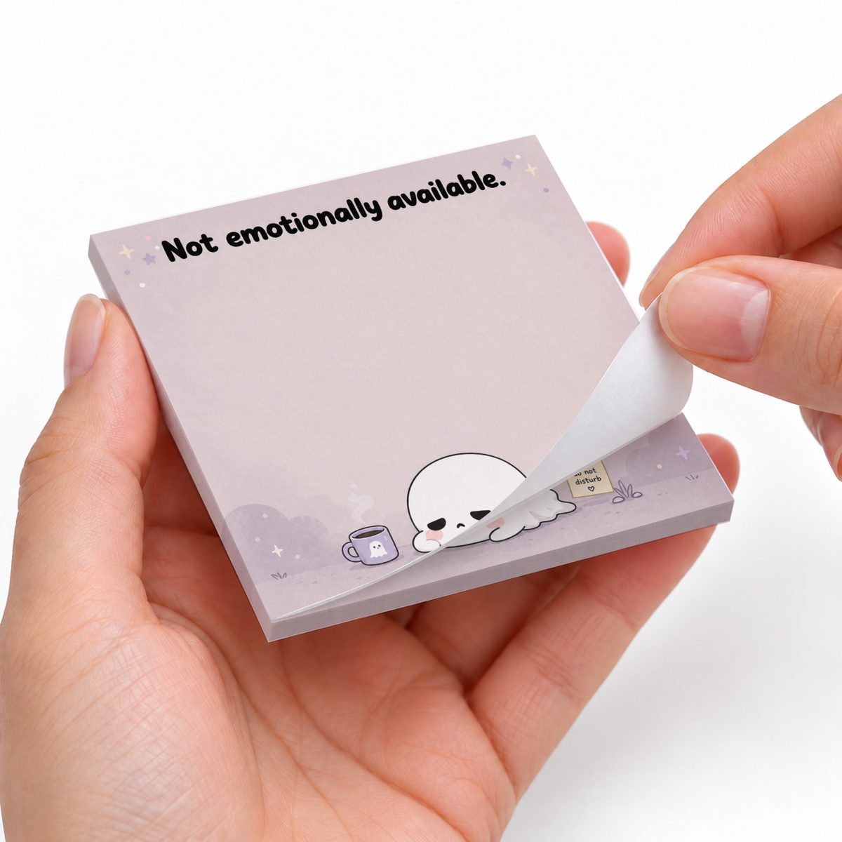Hands peel a sheet from a lavender ghost sticky note pad printed “Not emotionally available.”