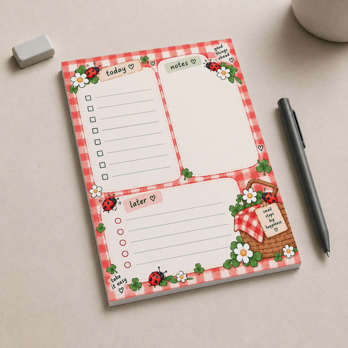 Ladybug Picnic Notepad on a desk beside a black pen and eraser, featuring a red gingham border and planning sections.