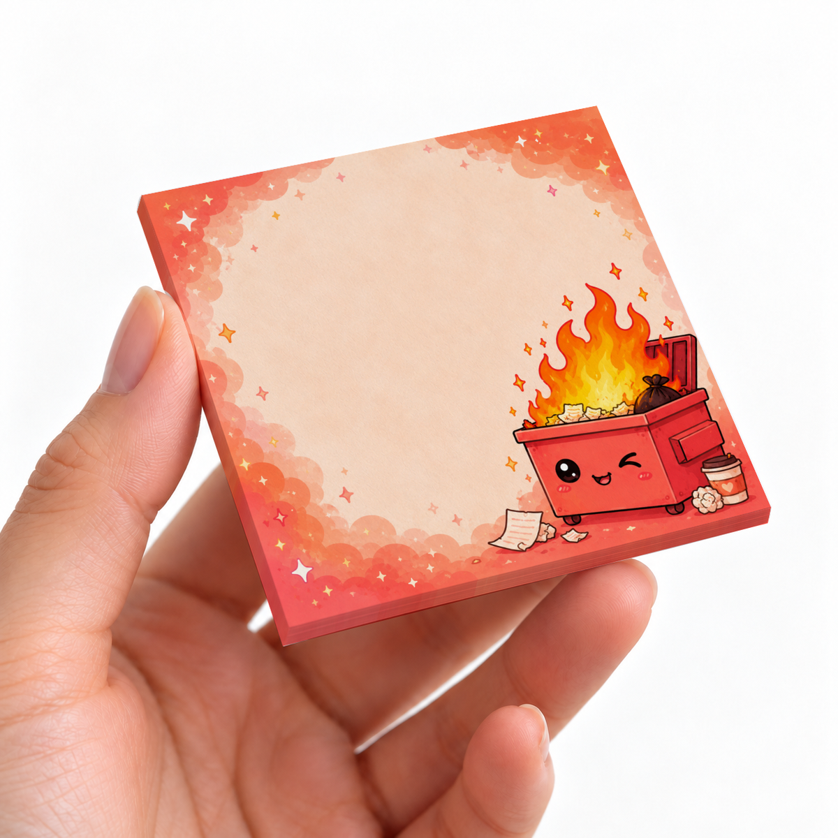 Hand holding a Winking Dumpster Fire sticky note pad with a peach writing area and sparkly red border.
