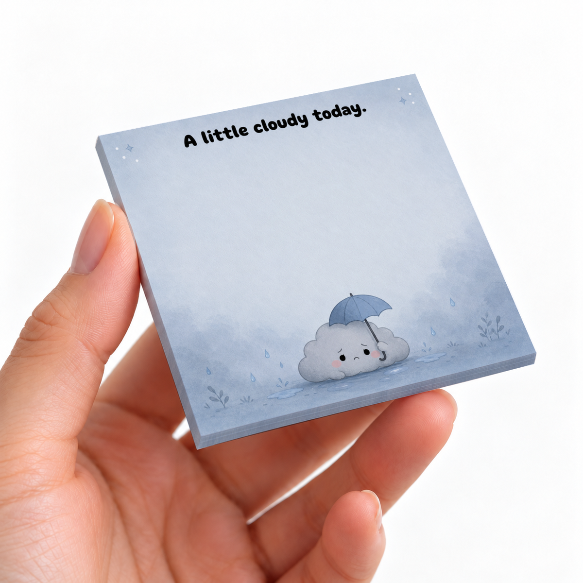 Hand holding a blue sticky note pad with “A little cloudy today” and a sad cloud under an umbrella.