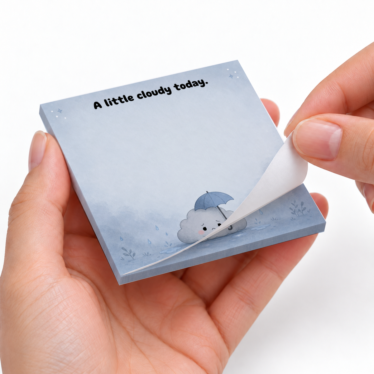 Hands peel a sheet from a blue 3 x 3 inch sticky note pad showing a cloud under an umbrella and “A little cloudy today.”
