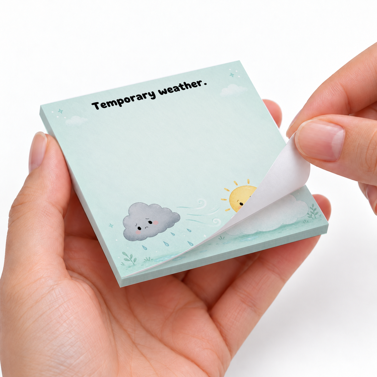 Hands peel a sheet from a blue 3 x 3 inch sticky note pad with cute cloud and sun art.