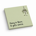 Pale green sticky note pad with a wilted hanging plant and the phrase “Hang in there. It gets worse.”