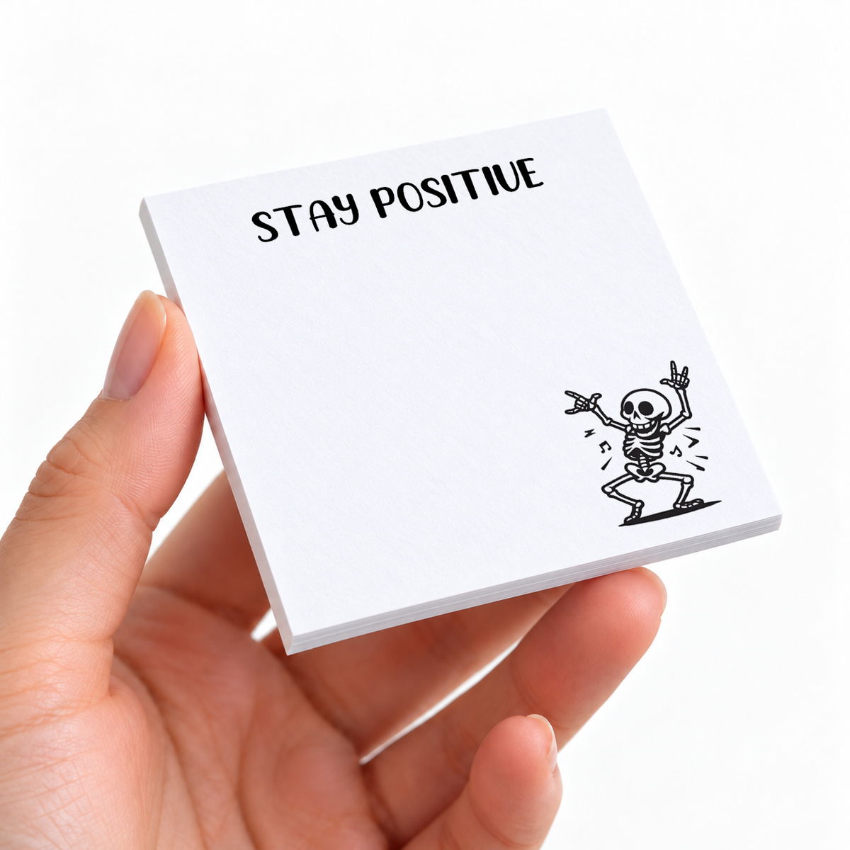 Stay Positive Dancing Skeleton sticky note pad on a desk with stationery